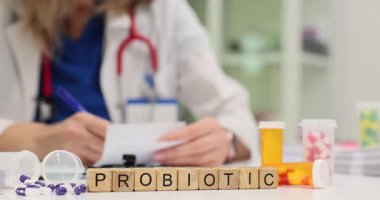 Tahta küplerle ilgili Probiyotik ve klinikte tıbbi kayıtları olan bir doktor. Kadın hekim, randevuda işyerinde oturan ilaçlara reçete yazar