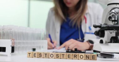 Tahta küplerin ve laboratuvar ekipmanlarının kelime testosteronu klinikte masanın üzerinde. Kadın doktor belgeleri. Randevuda kan örneklerini inceleyen test verileri.