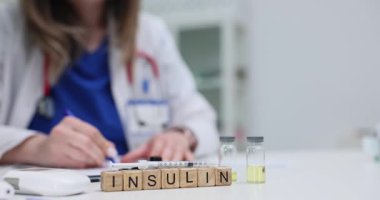 Doktor, hastane dolabında insülin ampulleri ve şırıngayla masada otururken reçete yazıyor. Yenilikçi diyabet tedavisi yavaş çekimde