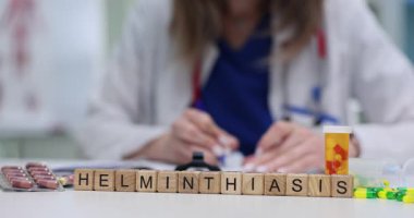 Doktor, masasında haplar ve kapsüllerle Helminthiasis tedavisi için reçete yazıyor. Etkili sağlık çözümlerinin önemi