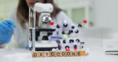 Laboratuvar teknisyeni moleküler modelin yanında mikroskopla oksikodon analiz ediyor. Modern klinikte ağrı yönetimi için araştırma ve geliştirme