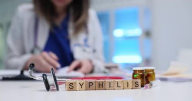 Tıbbi pratisyen doktor klinikteki masada otururken frengi tedavisi hakkında notlar alır. Modern hastanedeki frengi teşhisine odaklanın.