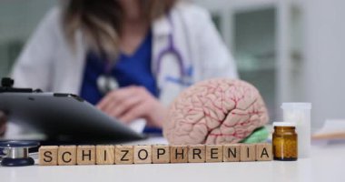 Doktor, insan beyninin anatomik modelinin yakınındaki şizofreni teşhisini analiz eden bir tablet bilgisayar üzerinde çalışıyor. Klinikte beyin tümörü tedavisi
