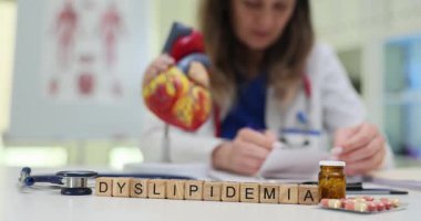 Doktor kalp ve hapların anatomik modelinin yakınındaki klinikte dislipidemi teşhisi ve tedavisini yazıyor. Glütenle ilgili araştırmalara odaklan.