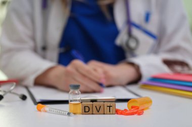 Doktor, masadaki şırınga ve çeşitli ilaçlarla DVT 'nin tedavi seçeneklerini tartışıyor.