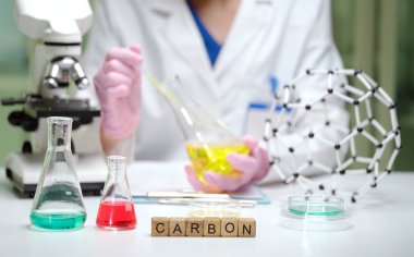 Kendini adamış bir bilim adamı modern bir laboratuvarda çeşitli karbon bileşikleriyle karmaşık deneyler yapıyor.