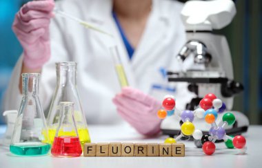 Canlı bir laboratuvar sahnesi canlı, renkli kimyasallar ve mikroskop ile heyecan verici florin deneylerini tasvir ediyor.