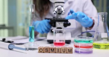 Kendini adamış bir araştırmacı gelişmiş laboratuvar ekipmanları ve mikroskop kullanarak osmiyum üzerinde deneyler yapar.
