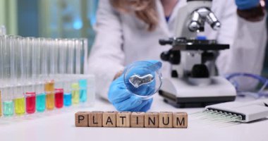 Parlak bir platin örneği, test tüpleri ve bilimsel analiz için mikroskobu olan bir laboratuvar sahnesi.