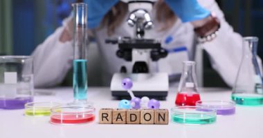 Kendini adamış bir bilim adamı modern bir laboratuarda renkli reaktörler ve laboratuvar ekipmanlarıyla Radon üzerinde çalışıyor.