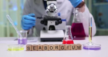 Canlı bir laboratuvar sahnesi, mikroskopla görülebilen renkli sıvılarla birlikte seaborjiyi gösteriyor. Bilim büyüleyici.