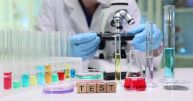 Bir bilim adamı, yüksek teknolojili bir laboratuvarda renkli sıvılar ve mikroskop üzerinde deneyler yapar.