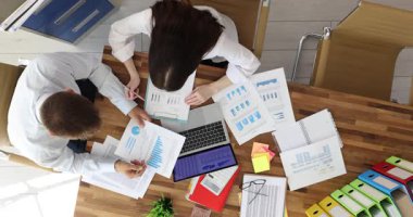 İş arkadaşları dizüstü bilgisayar ve hesap makinesi kullanarak finansal grafikleri ve grafikleri analiz eder. Modern ofiste yeni iş stratejileri