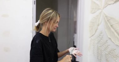 Sarışın kadın duvarda detaylı yardım heykeli ustalıkla hazırlıyor. Bayan bazı ayrıntıları vurgulamak için bazı bölgelere sıva uygular. Yavaş çekim