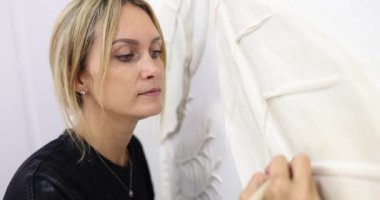 Yoğunlaştırılmış kadın, küçük model bıçakla levrek kabartma yüzeyi çizerek doku ekler. Yetenekli dişi yaprakların ana damarlarını yavaş çekimde oyar.