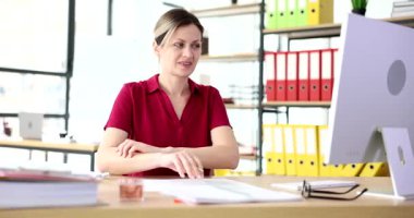 İş kadını masasında oturmuş bilgisayarla uğraşıyor ve raflarında renkli ciltlerle modern ofiste vücudu tırmalıyor. İş yerinde ağır çekimde alerji.