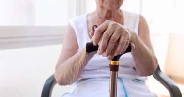 Kıdemli bir kadın, yaşlanma zorluklarını vurgulamak için bastona buruşmuş ellerini yapıştırıyor. Destek arayan yaşlılar için taşınabilirlik yardımlarının önemi