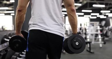 Kas sporcusu, dambılları üst vücut çalışmasına hazırlıyor. Çağdaş spor salonundaki dayanıklılık ve fiziksel uygunluğa odaklanın. Ağır çekim.