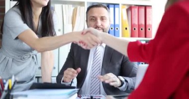 Kurumsal kadınlar el sıkışırken sakallı adam el çırpıyor işbirliği anlaşmasını onaylıyor. Modern iş ortamında başarılı müzakereler