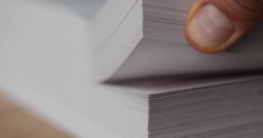 Parmaklar titizlikle dikkatli incelemeyi vurgulayan kalın kağıt yığınını çeviriyor. Profesyonel ofis ortamında evrak organizasyonu