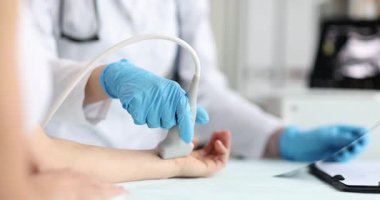 Mavi eldiven giyen doktor klinikte kadının bileğini ultrasonla muayene ediyor. Yenilikçi tanı teknikleri ve sağlık prosedürleri