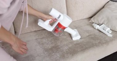 Ev hanımı koltuktaki toz ve kiri rahatça temizlemek için el yapımı elektrikli süpürge kullanıyor. Evi düzenli tutarken, temiz ve sağlıklı bir yaşam alanı
