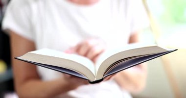 Odaklanmış kadın, sayfaları karıştıran büyük bir kitap okur. Kadın, edebiyatın hafta sonları boş zamanlarında bilgi ve eğitim kazanmasını seviyor