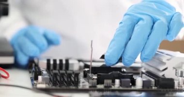 Koruyucu eldiven giyen teknisyenler işlemci mikroçipini elektronik anakartlara tam olarak yerleştiriyorlar. Hassas bilgisayar donanım kurulum süreci