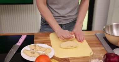 Kadın elleri mutfaktaki ahşap tezgahta hamur yoğurur. Genç ev hanımı ahşap masada tatlı için ev yapımı hamur işi hazırlıyor. Yemek pişirme