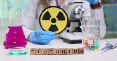 Bilimsel çalışmalar için kullanılan laboratuvar camlarıyla birlikte plütonyum sembolünü gösteren bir araştırma sahnesi.