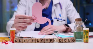 Bir doktor çeşitli antiülser ilaçlarını tartışırken midenin detaylı bir örneğini dikkatlice inceler.