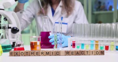 Yetenekli bir bilim adamı renkli çözümler ve karmaşık laboratuvar ekipmanları ile egzotermik bir reaksiyon gerçekleştirir.