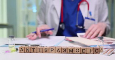 Bir sağlık uzmanı masa başında otururken çeşitli antispazmik ilaçları özenle analiz ediyor.