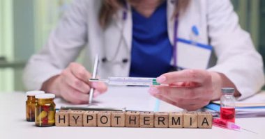 Bir sağlık uzmanı termometre ve uygun ilaç kullanarak hipotermi belirtilerini inceler.