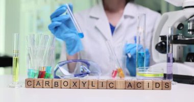 Bir bilim adamı renkli reaktörlerle dolu bir laboratuvarda karboksilik asitlerle çeşitli deneyler yapıyor.