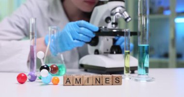 Bir laboratuvar teknisyeni mikroskop kullanarak aminlerle ilgili çeşitli örnekleri dikkatlice inceliyor.