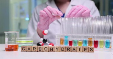 Bir bilim adamı, karbonhidratlar üzerinde deney tüpleri ve ekipmanlarla özelliklerini analiz eder.