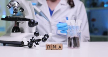 Bir bilim adamı RNA örneklerini mikroskop merceğiyle titizlikle inceliyor.