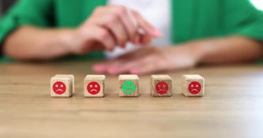 Kadın, kırmızı suratlı küplerin bir parçası olarak yeşil gülen yüzlü ahşap bloğa basıyor. Görevde olumlu geri bildirim sağlama eylemi