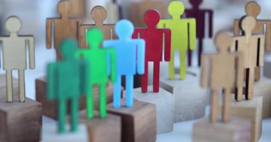 Farklı yüksekliklerdeki bloklara yerleştirilmiş kesim ahşap renkli insan şekilli heykelcikler. Düzenleme sosyal yapı kavramını öneriyor