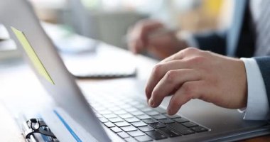 Klavyede hesap makinesindeki rakamları sayan adam tipleri rapor eder. İşadamı verimli bir iş gününde zamanı verimli bir şekilde kullanmak için çalışır.