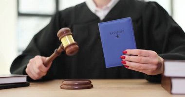 Adli bornozlu kadın elinde pasaport ve masa başında tahta tokmakla kapıyı çalıyor. Güçlü bir yasal otorite duygusu ve uluslararası seyahatlere odaklan