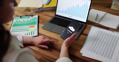 Telefon yükleme ekranını gösterirken kişi sabırsızlıkla parmaklarını tıklar. Tekrarlanan hareket, uzak çalışma süresince artan hayal kırıklığını ve gerginliği yansıtır