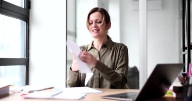 Yorgun kadın çalışan, ofiste yaratıcı krizin içinde yürürken kâğıt kırıntıları kırıyor. Kadın, masa başında iş için yenilikçi fikirler aramakta başarısız oluyor