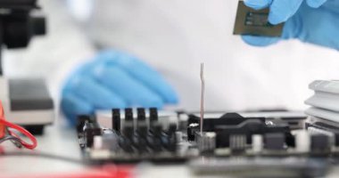 Bilim adamları eldiven takarak mikroçipi ana karta yerleştiriyor. Işık laboratuvara girer. Kesin işlem sırasında metal bileşenler üzerinde yansımalar yaratır.