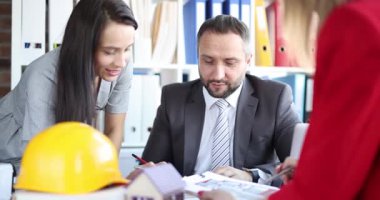 Profesyonel grup büro binası projesini tartışıyor. Mimar tasarımcılar şirket ofisinde kulübe çizimleri üzerinde birlikte çalışırlar.