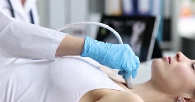 Hastanedeki kadın hasta tiroit bezinin ultrason muayenesi sırasında kanepede yatıyor. Cihaz araştırması yapan kadın doktor klinikteki vücut organlarını kontrol ediyor.