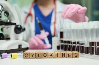 Bir bilim adamı deney tüpleri ve mikroskop kullanarak sağlık durumlarını anlamak için sitokinleri inceliyor.