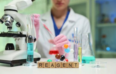 Kendini adamış bir bilim adamı modern bir laboratuarda önemli araştırmalar yapmak için laboratuvar reaksiyonları ve mikroskop kullanıyor.