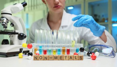 Bir bilim adamı, laboratuarda bilimsel araştırmaları gösteren renkli metal olmayan elementlerle deneyler yapıyor..